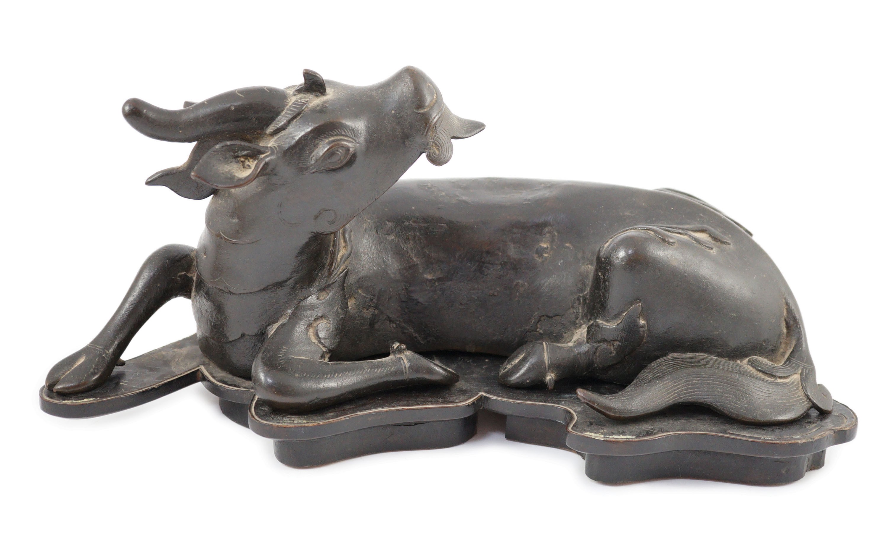 A Chinese bronze figure of a recumbent qilin, late Ming dynasty, 36cm long, old repairs and later base panel, wood stand